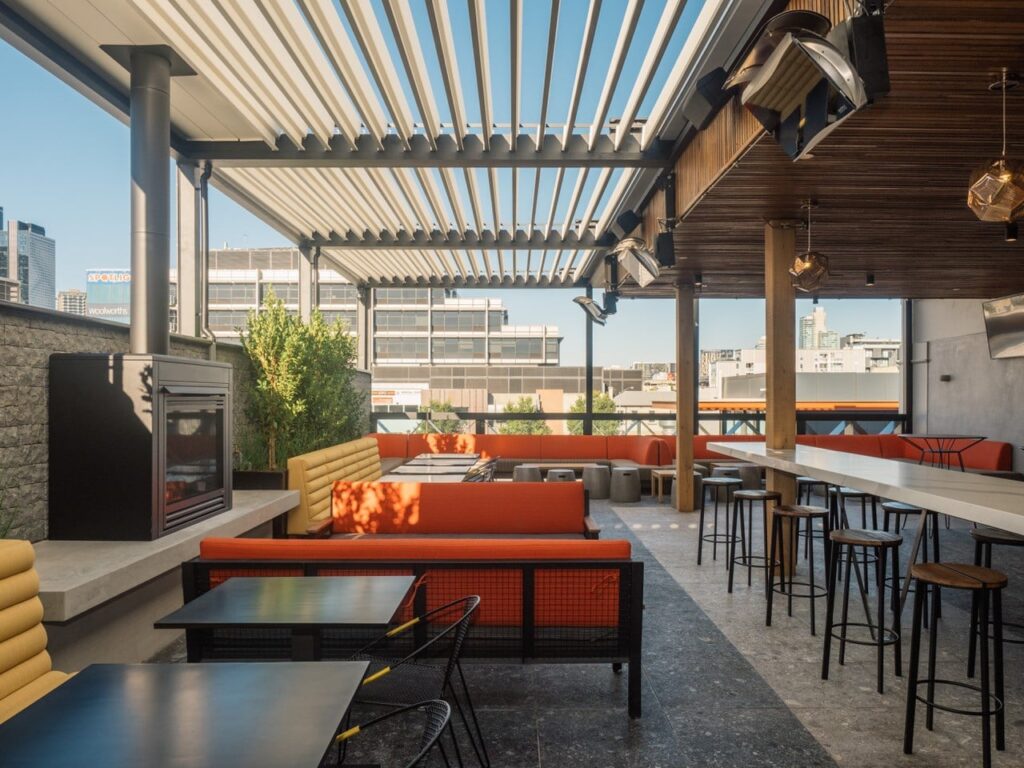 leere Bar und Restaurant auf dem Dach mit leuchtend orangefarbenen Liegestühlen und Gasheizungen
