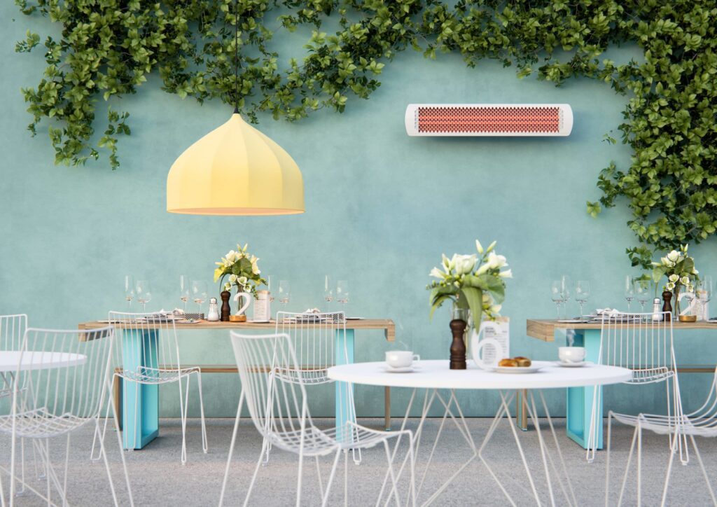 Weißer Heizstrahler auf grüner Wand in einem Innenhof