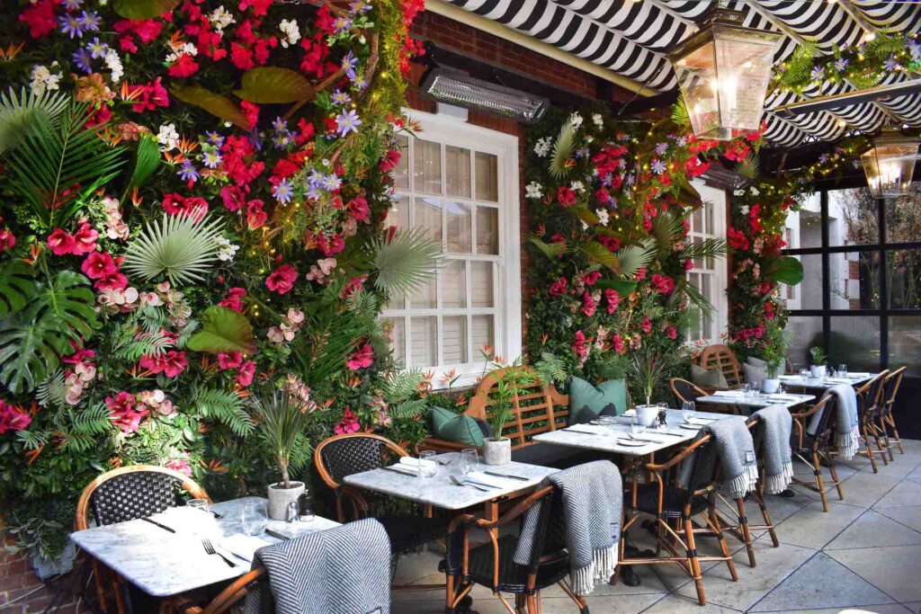 Bezauberndes Außenrestaurant mit hellen, geblümten Wänden und Decken über Korbstühlen, um die Gäste warm zu halten, sowie einer Bromic-Heizung